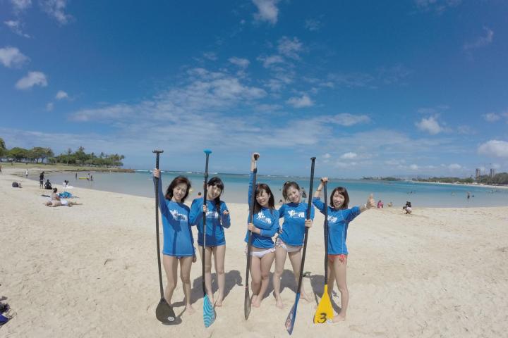 group of people standing on beach with paddles